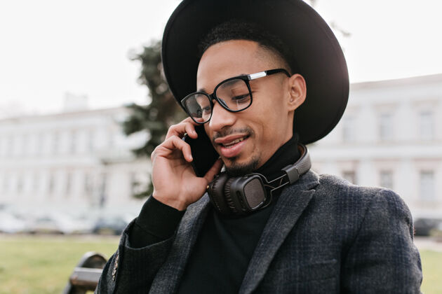 享受英俊的非洲年轻人打电话的特写照片戴时髦帽子的黑人打电话的户外照片帅气城镇电话