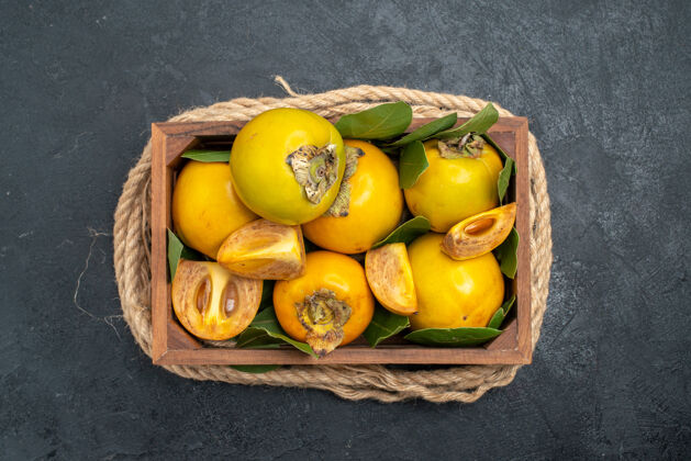 柿子顶视图新鲜甜甜的柿子在盒子里放在深色的桌子上品尝成熟的水果柑橘健康味道