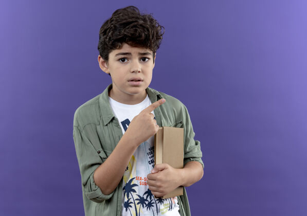 墙关心的小男生拿着书 指着隔离在紫色墙上的边和复印空间尖关心小学生