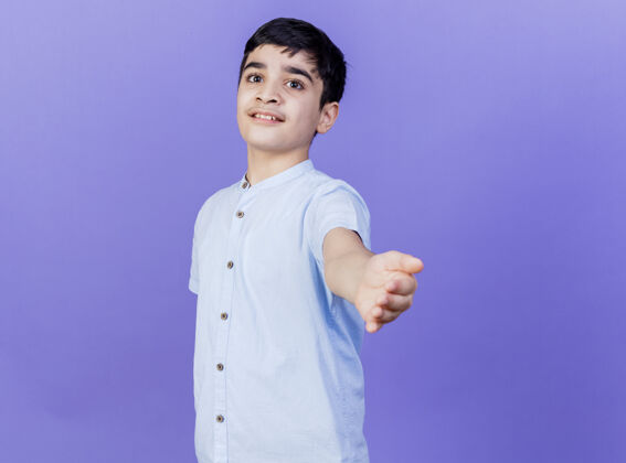 男孩令人印象深刻的年轻白人男孩站在侧视图看着相机伸出手对着相机孤立的紫色背景与复制空间年轻紫色印象