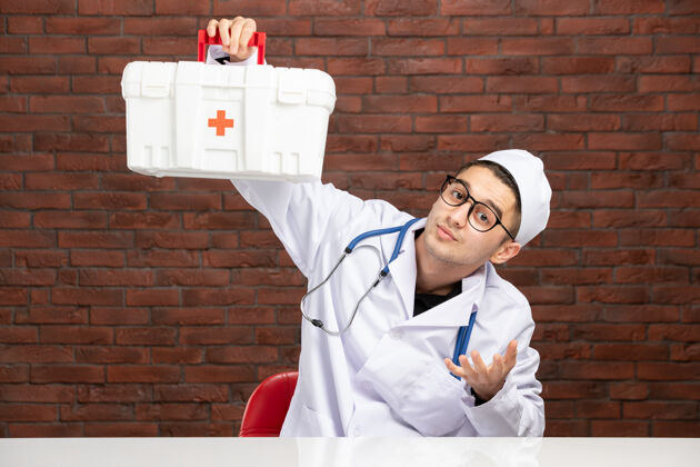 砖头前视图身穿白色医疗服的年轻医生带着急救箱白色男子医院