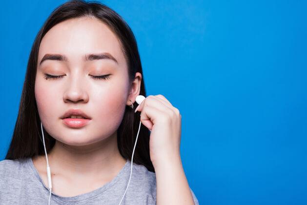 人戴着耳机听音乐的亚洲女人欢呼成人封闭