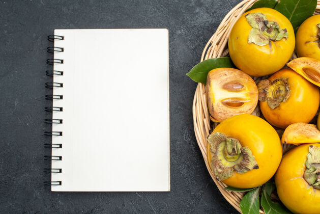 蔬菜顶视图新鲜甜甜的柿子在篮子里放在深色的桌子上 成熟的水果醇厚成熟黄色篮子