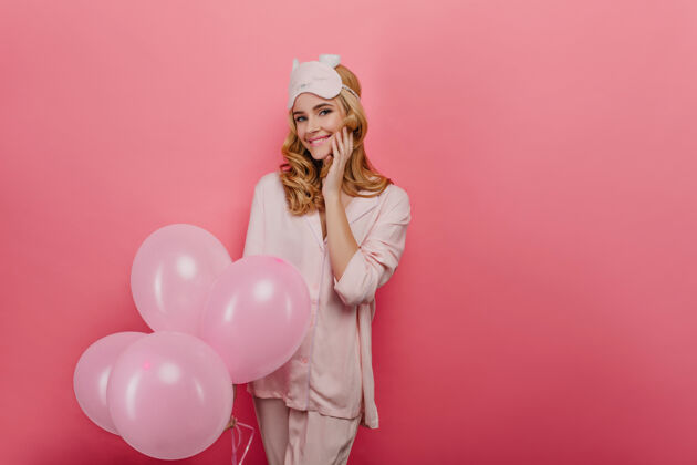 舞蹈兴奋的生日女孩等待礼物的肖像穿着睡衣的感兴趣的女模特手持一束粉红色气球的照片女人微笑肖像