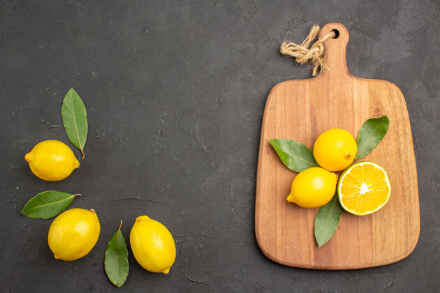 多汁顶视图新鲜的酸柠檬和叶子放在一张深色的桌子上水果柠檬黄色的柑橘健康深色水果
