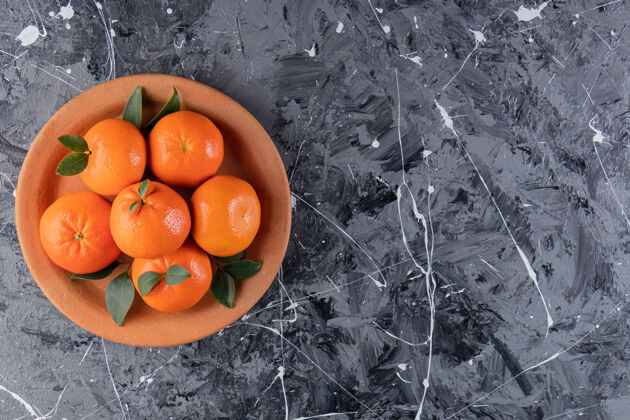 叶子整个新鲜的橙色水果 叶子放在泥盘里甜点有机柑橘