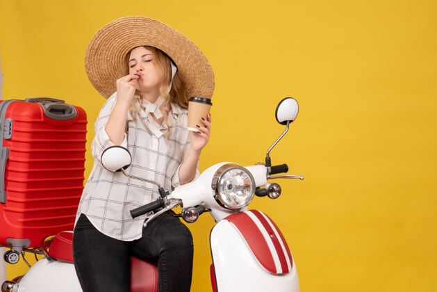 年轻女子戴着帽子坐在摩托车上出示车票的梦幻女郎漂亮帽子摩托车