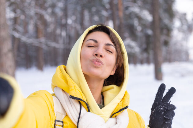 手机年轻美丽快乐开朗的女子在冬季森林视频博客 自拍照片寒冷成人公园