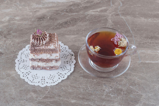 美味一杯茶和一块蛋糕放在大理石上的小垫子上糕点美味茶