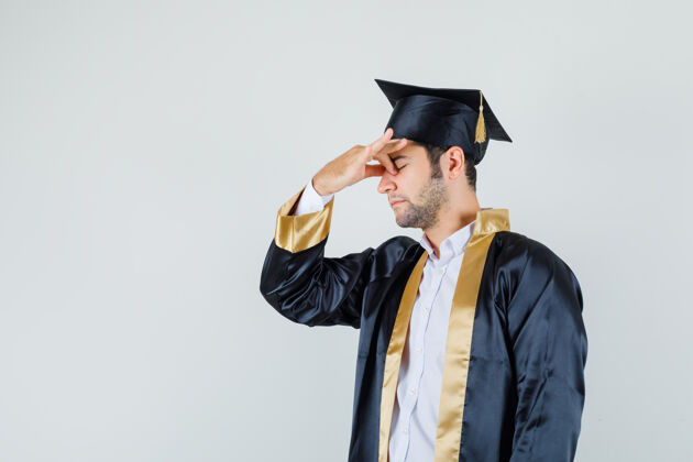 鼻子穿着毕业制服的年轻人揉着眼睛和鼻子 看上去很累 前视制服毕业聪明