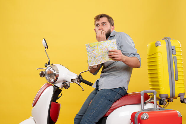 成人旅游概念与年轻的恐惧胡须男子坐在摩托车上 并显示它的黄色地图坐着摩托车地图