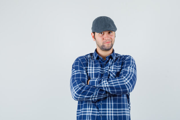 休闲年轻的男性交叉双臂站在蓝色衬衫 帽子和看起来自信 正面视图孩子虚拟手臂