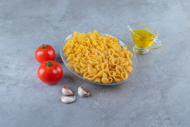 黄色把生的意大利面和生的干的意大利面放在一个玻璃碗里烹饪面食一餐