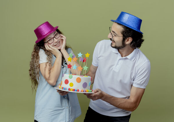 绿色一对戴着粉蓝相间帽子的年轻人微笑着把生日蛋糕送给被隔离在橄榄绿上的快乐女孩女孩蛋糕男孩