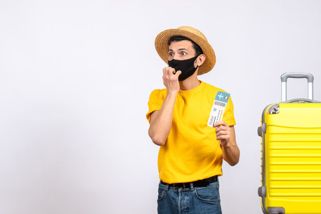 稻草前视图困惑的年轻人戴着草帽站在黄色手提箱旁边拿着旅行票旅行帽子人