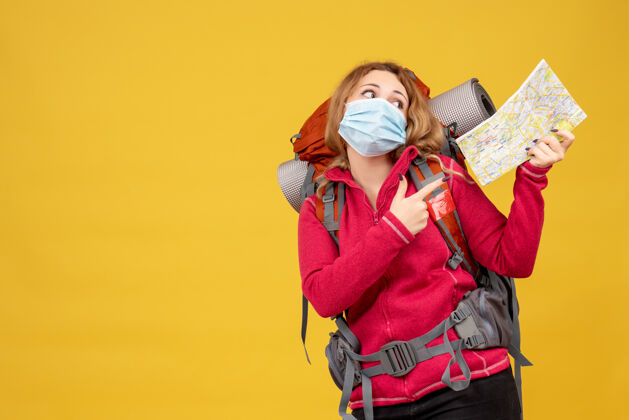 行李顶视图年轻的旅行女孩在医疗面具收集她的行李和显示地图顶展示人