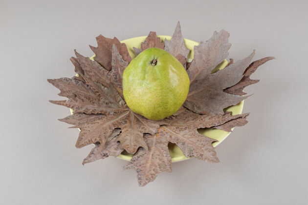 叶一棵梧桐树的叶子放在大理石盘子上的一个梨下面饮食新鲜有机