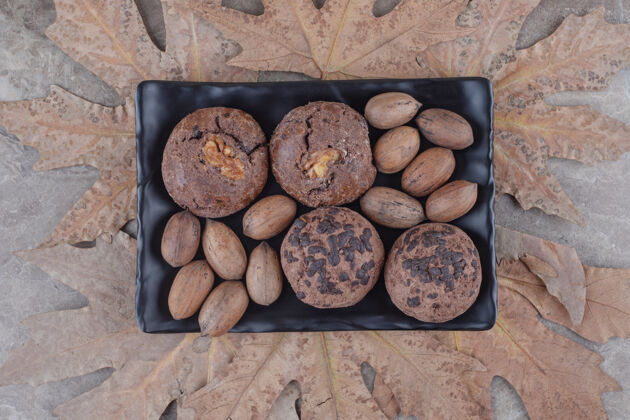 小吃盘子里放着一捆饼干和山核桃 大理石上放着一捆梧桐树叶坚果美味山核桃