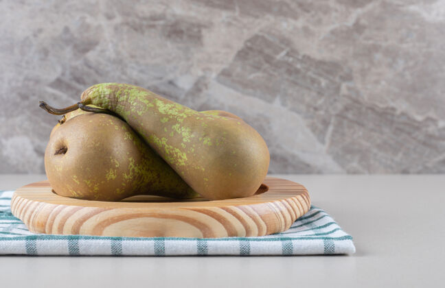 风味一捆美味的梨放在毛巾上的木盘上 放在大理石上健康梨天然