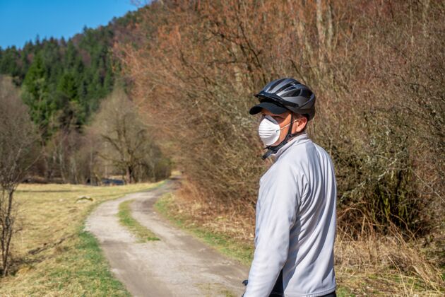 娱乐戴着防护面具的人在冠状病毒\/冠状病毒-19期间骑自行车自然道路单独