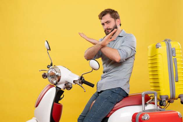 车辆旅行概念的正面视图 年轻人坐在摩托车上 手提箱在黄色的摩托车上做停车手势年轻人成人摩托车