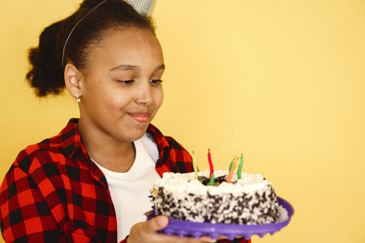 快乐小女孩生日被隔离在黄色的墙上孩子拿着蛋糕年轻漂亮蜡烛