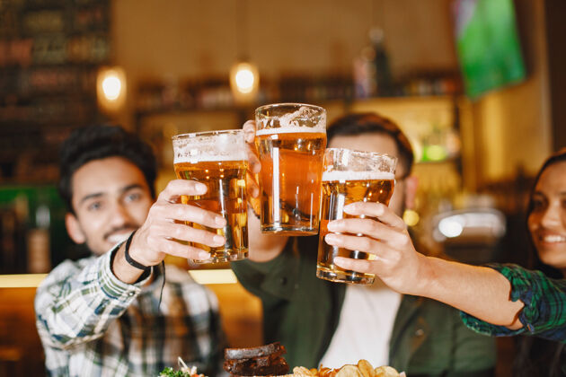 伴侣酒吧里的印度朋友酒吧里的男女朋友喝着啤酒庆祝吃水印度微笑