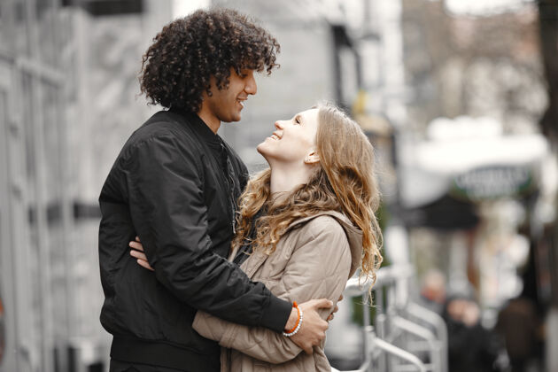 金发穿着外套在街上拥抱的年轻夫妇情侣成人年轻