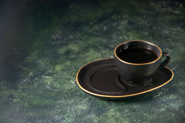 茶碟前视一杯红茶 茶杯和碟子放在深色的表面上 糖仪式 玻璃早餐蛋糕 甜点 彩色糖果盘子杯子前面