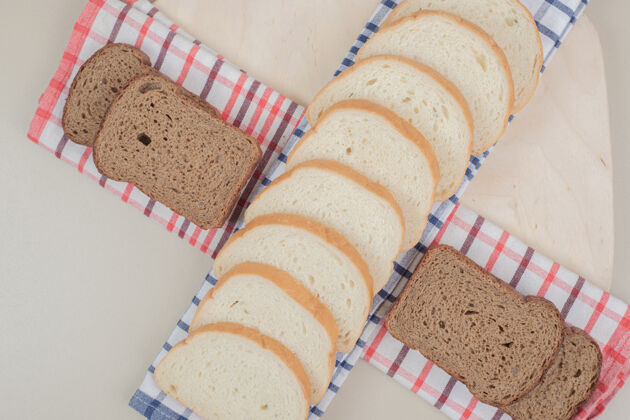 美味把新鲜的白棕色面包片放在桌布上可口烘焙营养