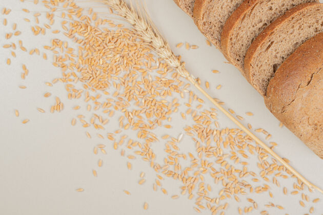 谷物切片新鲜的棕色面包 白色表面有燕麦粒美味面包糕点