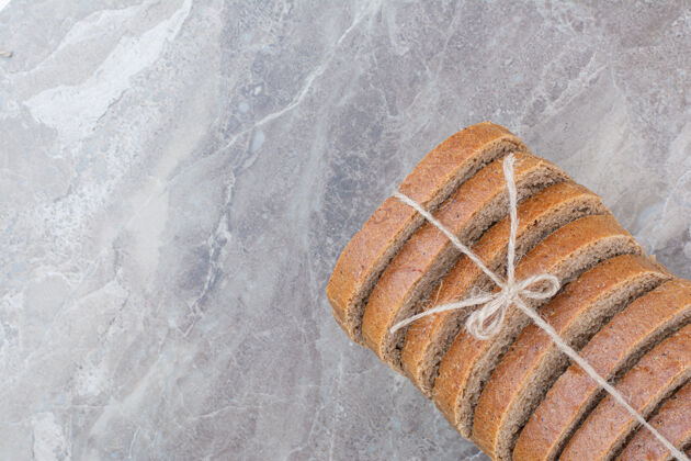 整个用绳子把棕色面包片放在大理石表面面包面包膳食