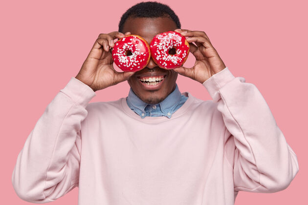 衬衫年轻的非洲裔美国人拿着美味的甜甜圈年轻肖像人