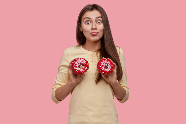 成年人年轻的黑发女人拿着美味的甜甜圈肖像人美味