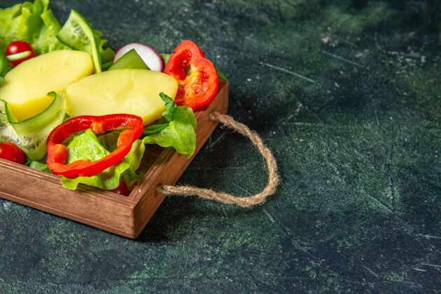 素食半拍新鲜切碎的蔬菜在一个木托盘上混合颜色的表面与自由空间沙拉甜瓜一半