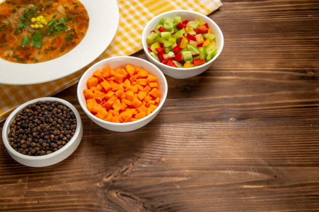 木头在棕色的木桌上可以看到美味的蔬菜汤和蔬菜片美食桌子前台