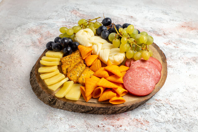 健康前视不同的小吃cips香肠奶酪和新鲜葡萄在白色空间不同水果前