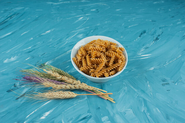 通心粉一碗白色的干意大利面 蓝色背景上有小麦穗面食烹饪烹饪