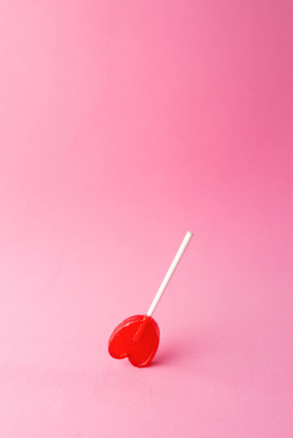 形状粉红色背景上的一个心形棒棒糖的垂直镜头甜点心食物