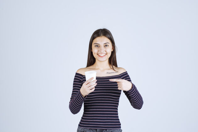 成人穿着条纹衬衫的女孩拿着一个塑料咖啡杯 介绍它是一种产品聪明人人体模特休闲