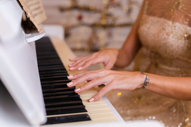 优雅穿着金色圣诞晚礼服在家弹钢琴的女人浪漫经典键盘