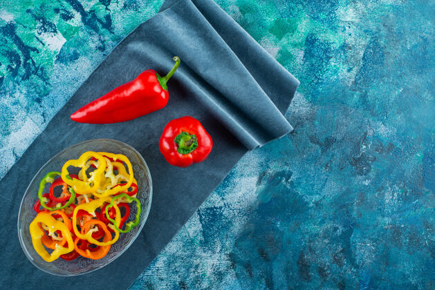 蔬菜把什锦辣椒片放在一个碗里 旁边是一块布上的红辣椒 背景是蓝色的辣椒好吃碗