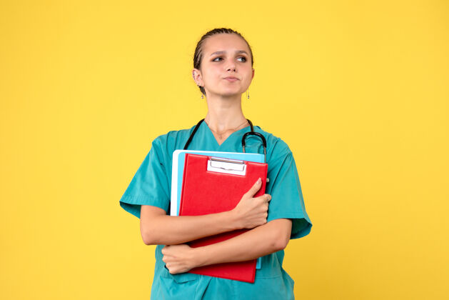 情绪黄色墙壁上穿着不同分析的医疗服的女医生的正面图人女医生护士