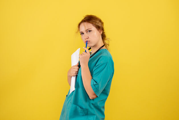护士黄墙上穿着医疗服的女医生手持分析图医疗人女医生