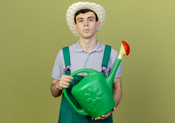 男性自信的年轻男园丁戴着园艺帽拿着浇水罐园艺复制绿色