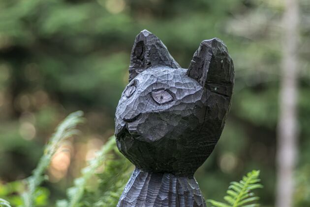 猫一个木制黑猫雕像的特写镜头在阳光下的田野里 背景模糊乡村农场雕刻