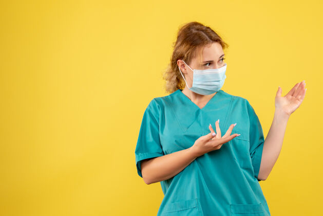 男性黄色墙壁上穿着医疗服 戴着口罩的女医生的正视图大流行病毒健康