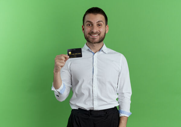 男人笑容可掬的帅哥把信用卡隔离在绿墙上英俊绿色优雅