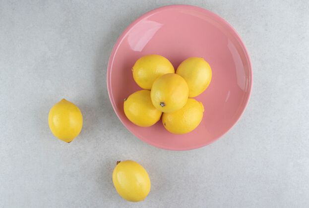 天然粉红色盘子里有一堆黄色的柠檬柑橘水果成熟
