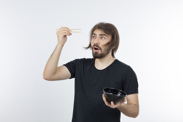 人一个留胡子的男人拿着筷子在白色的墙上拿着碗站着摆姿势人